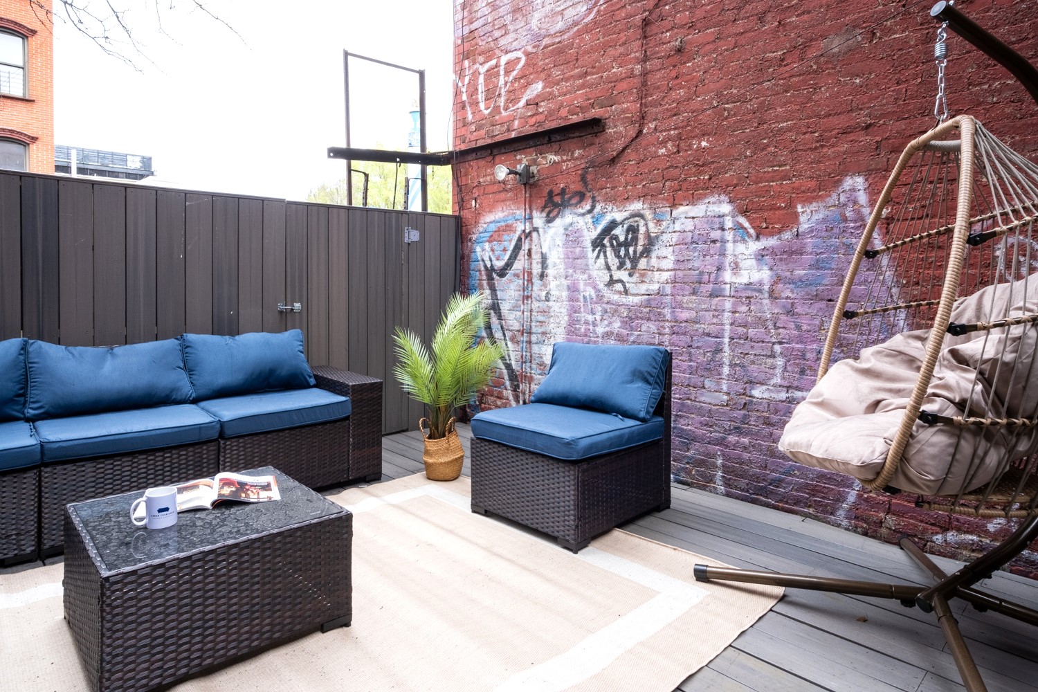 Private patio with blue sectional against a red brick wall